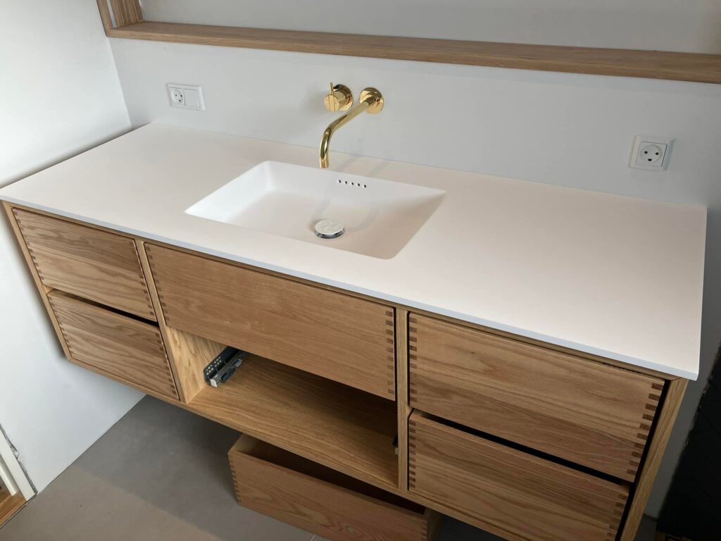 Moderne badeværelsesvask med træskabe og hvid bordplade