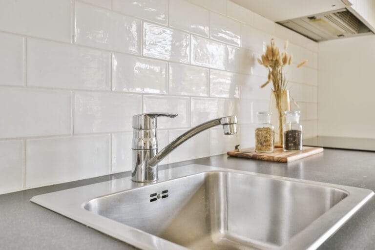Moderne køkkenvask med blank armatur og flisevæg